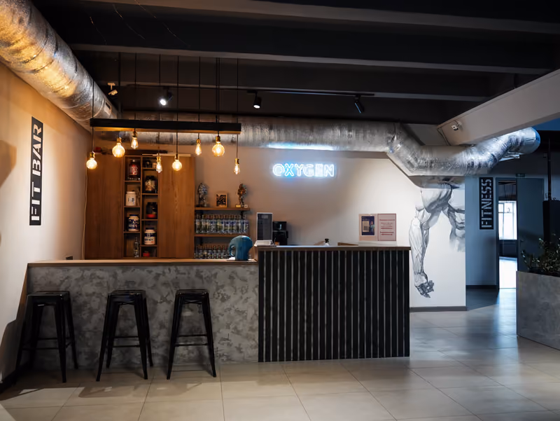 Fit bar клуба с неоновой вывеской OXYGEN и барными стульями.